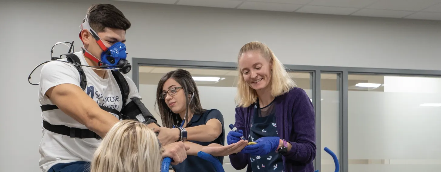 Group of exercise physiology students and teacher conducting assessment in kinesiology lab.